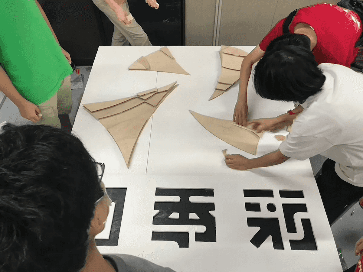 $先輩方が、切り出したベニヤの置き場所と重ね方を話し合っています。
