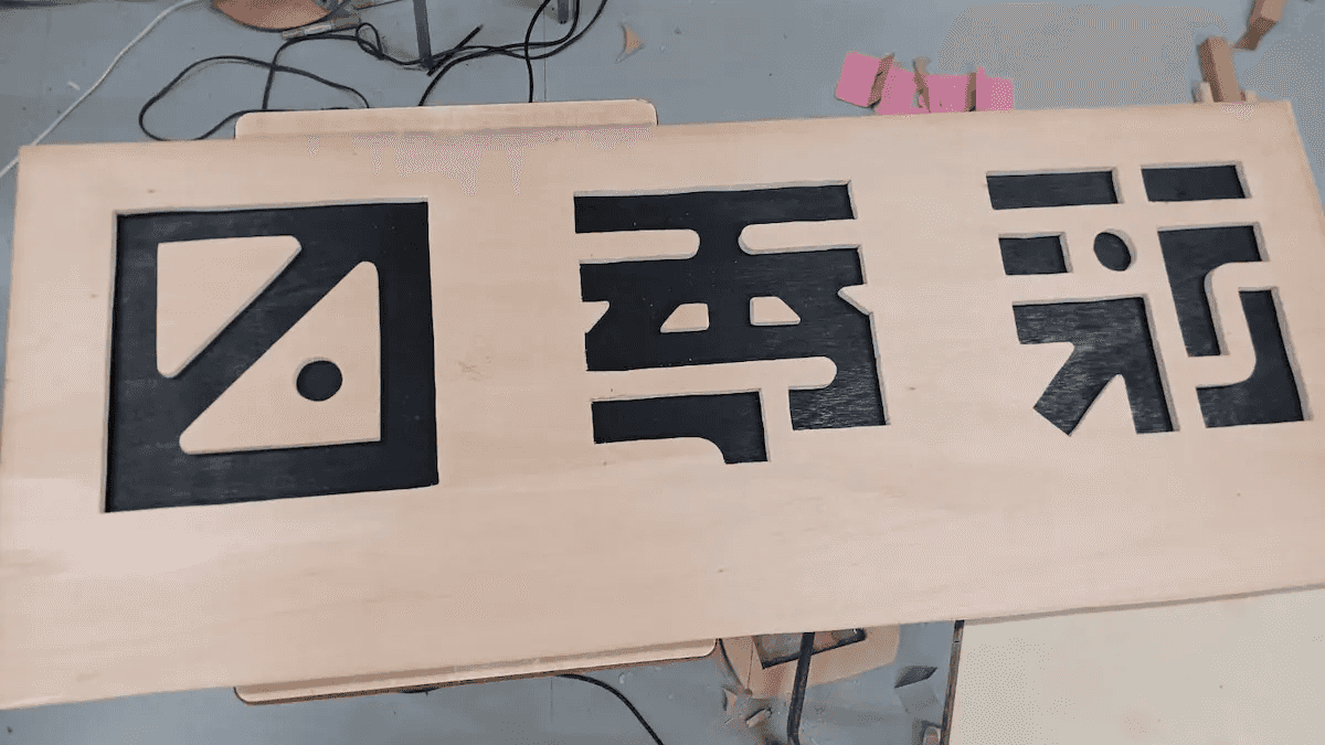 $スプレーで黒く塗ったベニヤ板に、ジグソーで文字をくり抜いた板を重ねました。くり抜いた方の板はこの後白く塗られます。